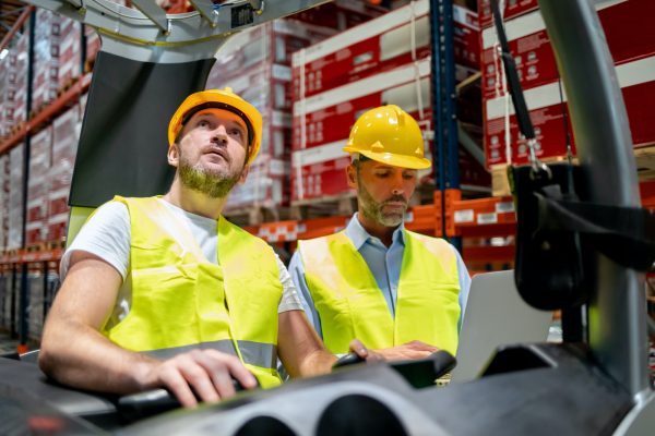 Warehouse worker learns how to use forklift with instructor Warehouse worker learns how to use forklift with instructor